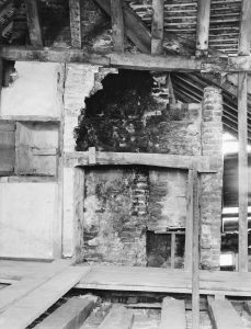 Image shows raised floorboards and partially broken through walls in the upper room of Maison Dieu