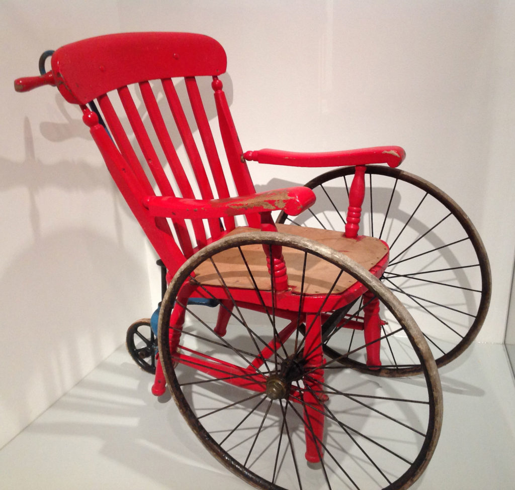 Red painted wooden chair mounted on wheels