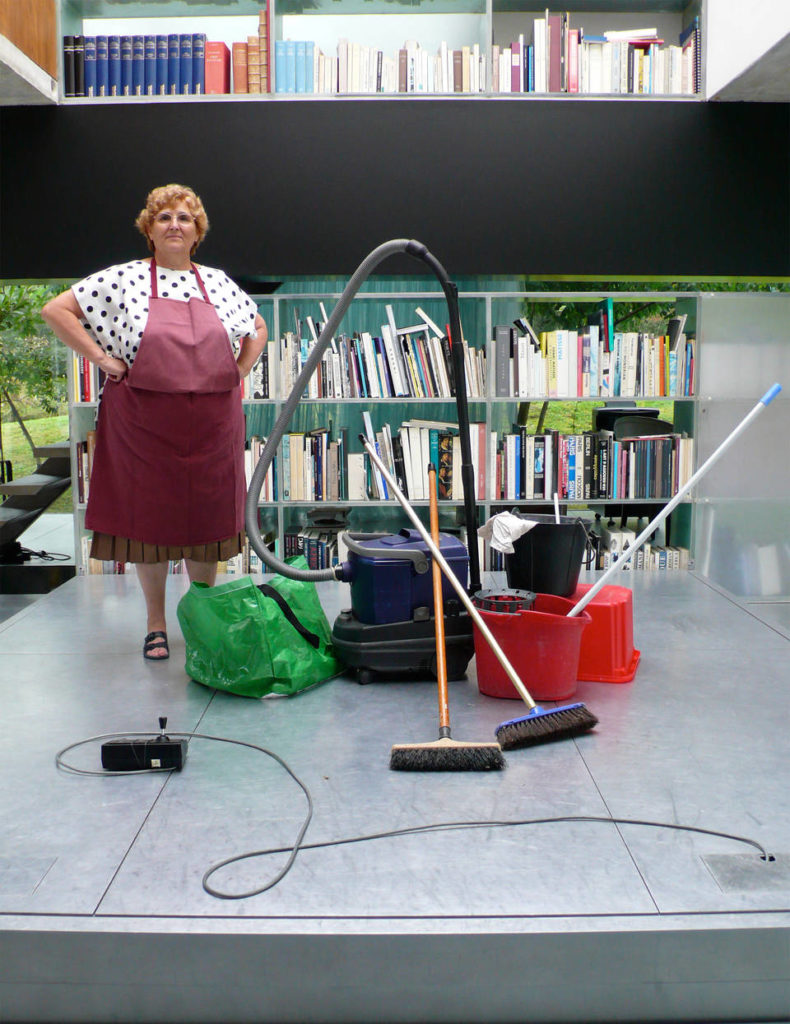 Woman with cleaning equipment stands on the large moving platform between floors