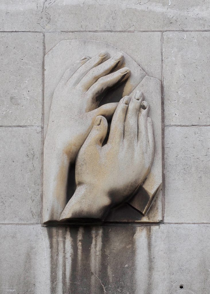 Relief sculpture from the Royal School for the Blind in Liverpool showing two hands reading braille.