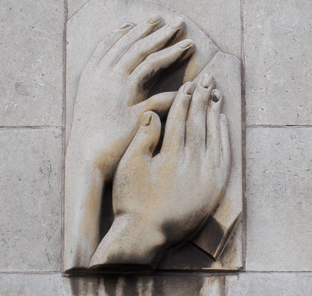 Relief showing hands reading braille on the side of the School's extension.