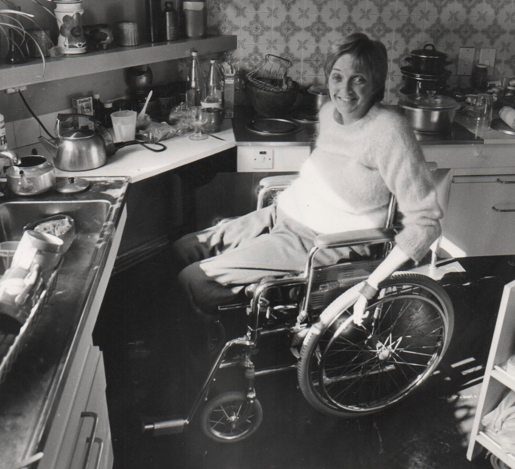 Woman in wheelchair in 70s kitchen