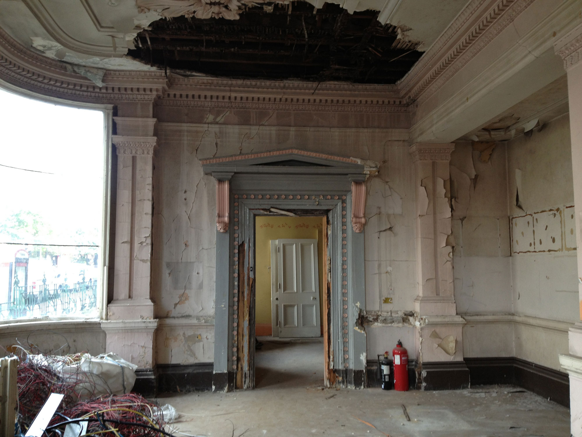 Crumbling paintwork on a grand interior with neoclassical scrollwork around a blue door.