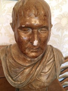 Image shows bust of man covered in gold and with Roman senator style cloth wrapped around his upper chest