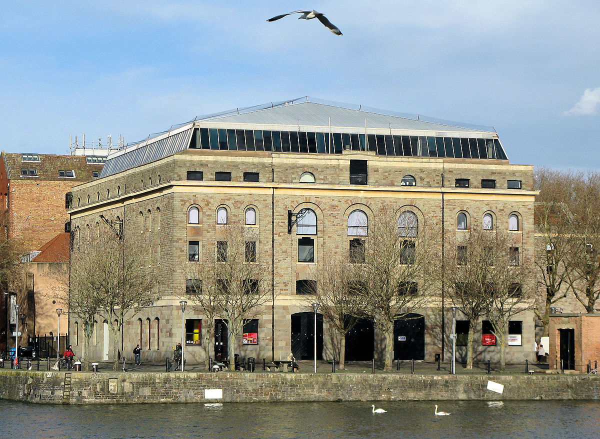 Image shows imposing building with arched and square windows next to the Bristol waterfront