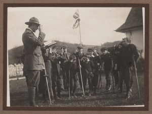 Man in Scout dress and boys with crutches with a union jack in a garden