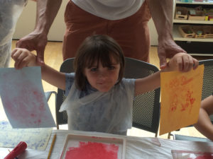 Small girl shows off her monoprints from workshop