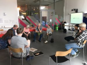 Participants sit on chairs in a circle sharing story ideas