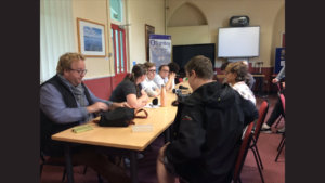 A group of approximately ten people are sitting around a long table