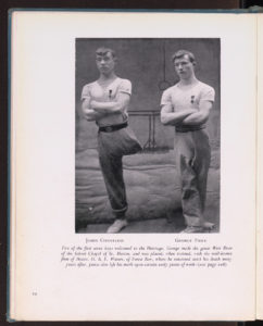 Two young men with arms folded, one with one trouser leg pinned up.